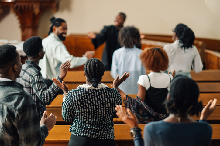 Congregation of Black worshippers standing and praising during a church service